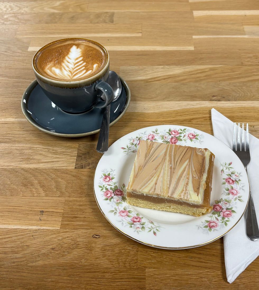 A latte with latte art and a slice of cake